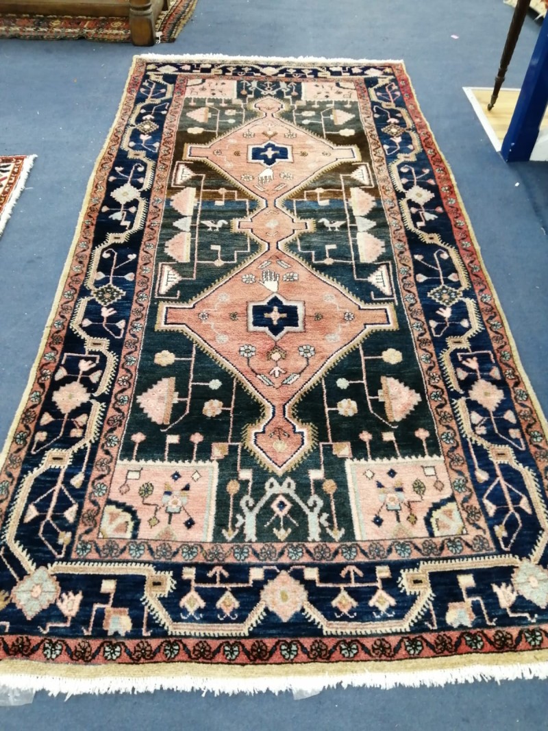 A Turkish rug, dark blue/brown ground centred by a rose pink double lozenge, 267 x 142cm